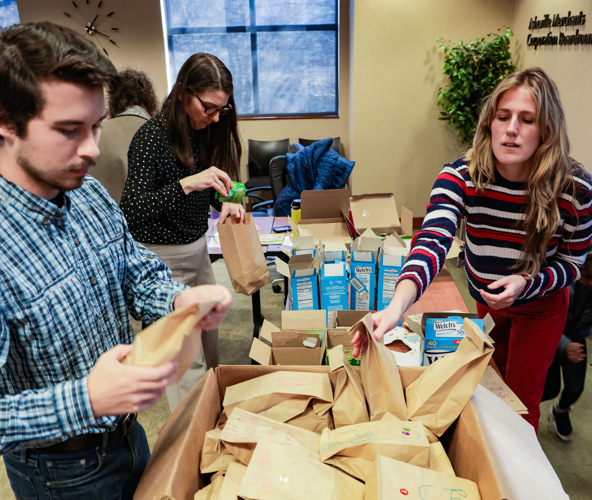 Asheville Chamber of Commerce place over 100 snack packages into a bow so that they may be distrobuted to children and families who are supported by the BCS Migrant Education Program.