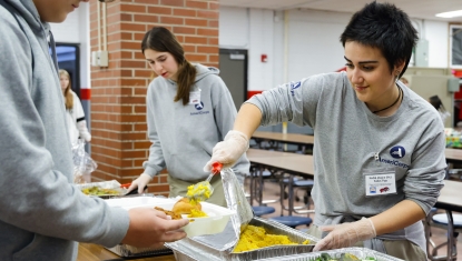 AmeriCorps member serving food at a local school